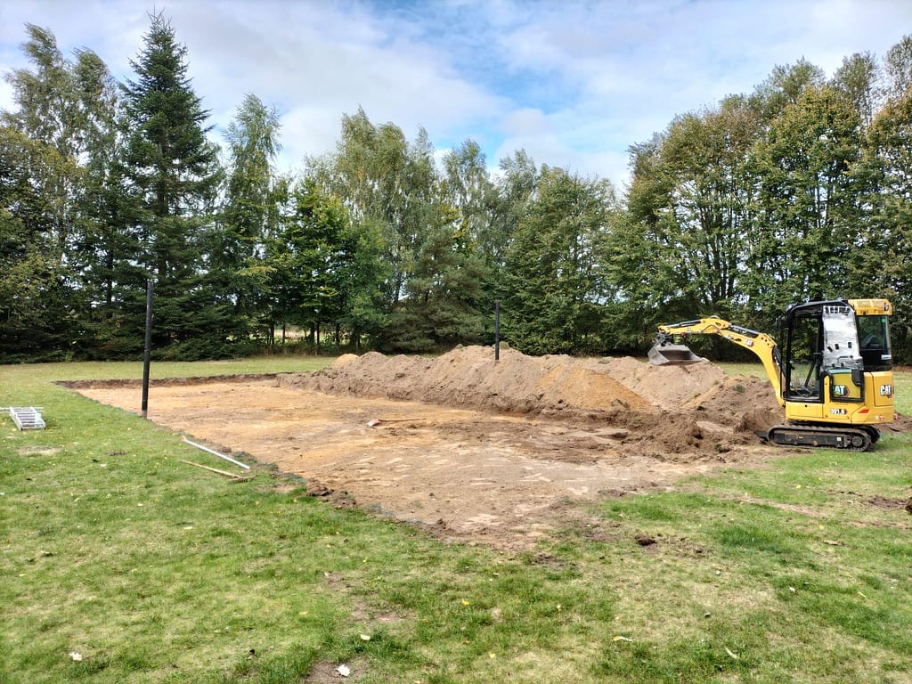 Bager hebt ein Volleball feld aus.