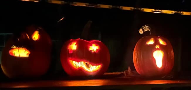 Drei Halloween-Kürbisse mit gruseligen Gesichtern, bei nacht.